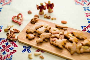 Gingerbread with almonds on a wooden tray and a decorative cloth with heart and angels in the background