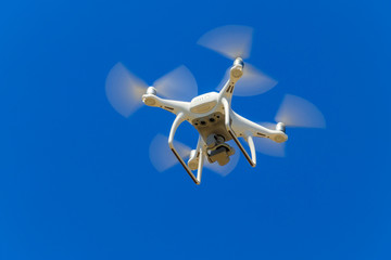 Naklejka na ściany i meble Drone with camera flying in blue sky