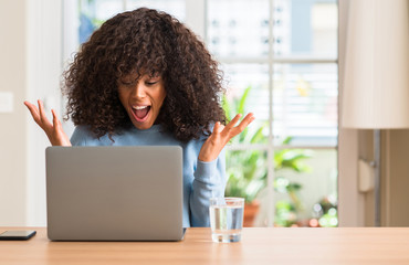 African american woman using laptop computer at home very happy and excited, winner expression...