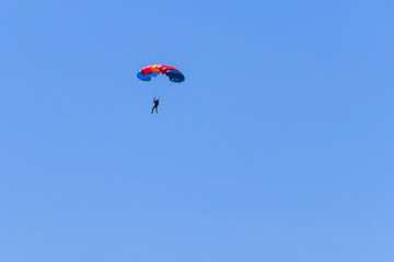 Fototapeta na wymiar Parachutist descending with a parachute against blue sky
