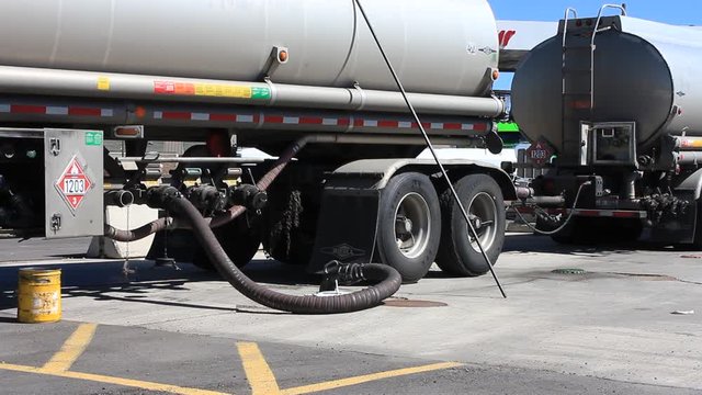 Gas Station being filled with fuel. Measuring stick resting against the semi truck.