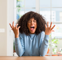African american woman at home crazy and mad shouting and yelling with aggressive expression and...