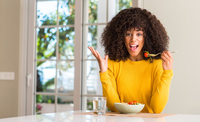 Fototapeta na wymiar African american woman eating pasta salad very happy and excited, winner expression celebrating victory screaming with big smile and raised hands
