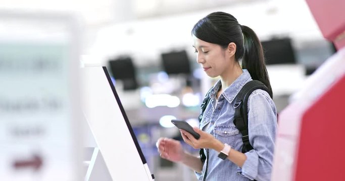 Woman using selfie check in machine in the airport