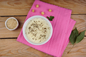 Rice soup with herbs on a table with a pink napkin