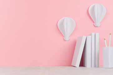 Pile white books and decorative hot air balloons of papers on white desk and soft pink background....