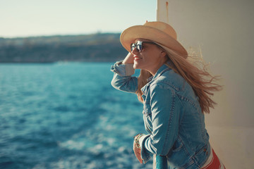 Blonde traveler woman on sea in hat looking away