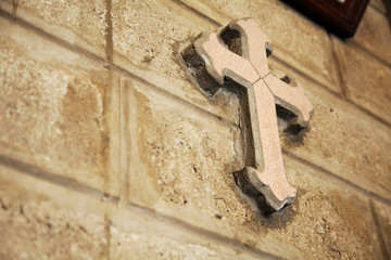 Decorative cross on a catholic church brick wall. Symbol of Christianity background with copy space. Chapel decoration detail