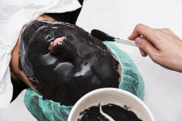 Beauty doctor apply skin alginate seaweed black mask to male patient face