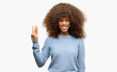 African american woman wearing a sweater showing and pointing up with fingers number three while smiling confident and happy.