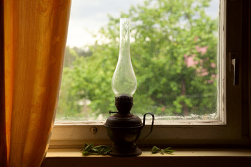 Vintage kerosene lamp on the windowsill, rustic still life, retro object
