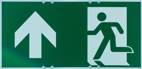 Sign with the pictogram of a walking person and an arrow in white on a green background, indication...