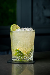 cold cocktail with lime and lemon. A glass of dew drops. Freshness, alcohol, bar. Black background