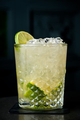 cold cocktail with lime and lemon. A glass of dew drops. Freshness, alcohol, bar. Black background