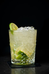 cold cocktail with lime and lemon. A glass of dew drops. Freshness, alcohol, bar. Black background