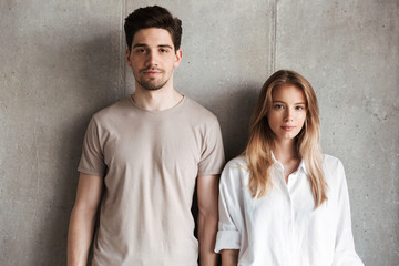 Young loving couple standing over grey wall