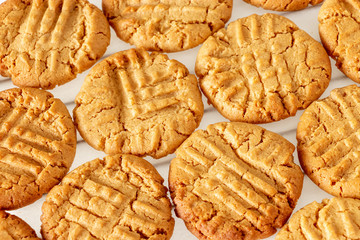 Delicious homemade peanut butter cookies on cooling rack. White wooden background. Healthy snack concept.