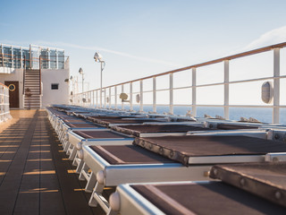 Naklejka premium Empty sea deck of a cruise ship at dawn in the open sea against a blue sky and a bright sun
