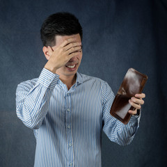 Portrait Handsome young asian man wearing a blue shirt stressed because empty wallet no money isolated on back wall background. Businessman concept. Asia people.