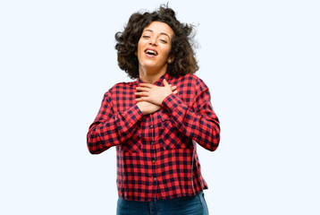 Beautiful arab woman having charming smile holding hands on heart wanting to show love and sympathy