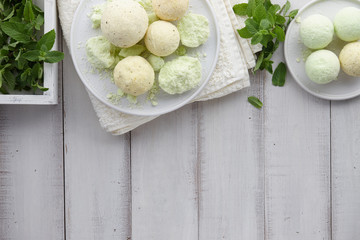 Handmade mint and lemon bath bombs and towel on white wooden planks, top view. Natural cosmetics...
