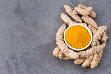 Turmeric powder and fresh turmeric on wooden background - Curcuma longa