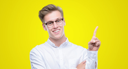 Young handsome blond man with a big smile on face, pointing with hand and finger to the side...