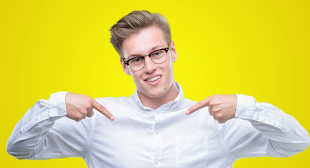 Young handsome blond man looking confident with smile on face, pointing oneself with fingers proud...