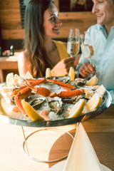 Image of Close-up of fresh oysters and crabs served on ice with slices of lemon at the table of a romantic young couple eating at restaurant printed on Printed Glass Basin Splashbacks