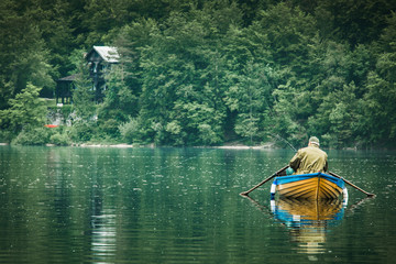 retired old man fishing from boat at lake