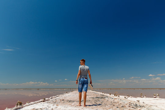 Young man is standing in a pink salt lake