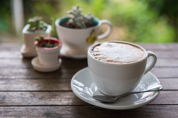 Cappuccino cup coffee with plants on old wooden table