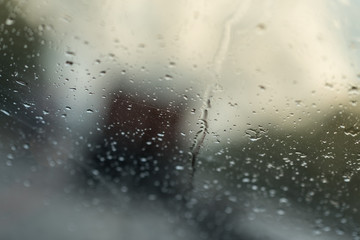 Raindrops on glass car window with road light bokeh. water drop on the glass, evening storm.