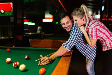 Young couple playing snooker together in bar