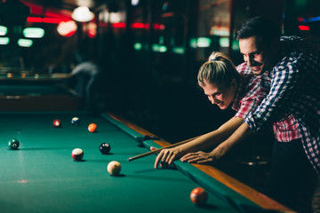 Young couple playing snooker together in bar