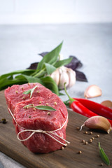 Raw beef steak with ingredients for cooking on cutting board .