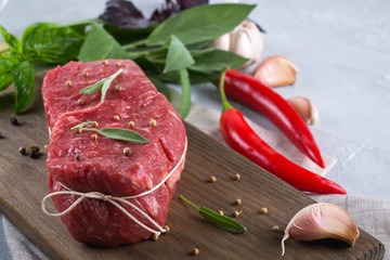 Raw beef steak with ingredients for cooking on cutting board .
