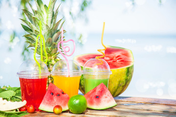 Fresh healthy juices, fruit, pineapple, watermelon on the background of the sea. Summer, rest, healthy lifestyle Copyspace