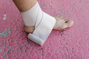 Male athlete applying compression bandage onto ankle injury of a football player, Sports injuries.