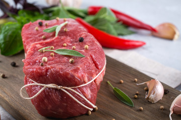 Raw beef steak with ingredients for cooking on cutting board .