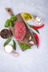 Raw meat. Raw beef steak on a cutting board with greens and spices.