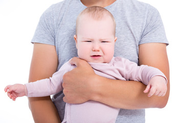 portrait of crying baby girl on father's hands isolated on white