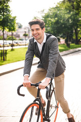 Cheerful young businessman riding on a bicycle