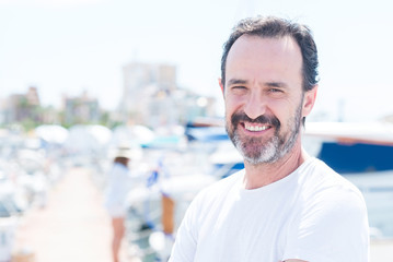 Handsome middle age man in marina with a happy face standing and smiling with a confident smile showing teeth