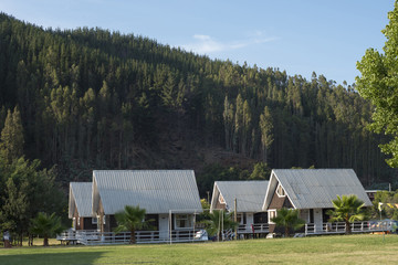 Fototapeta na wymiar Cabins in green summer mountain holiday landscape