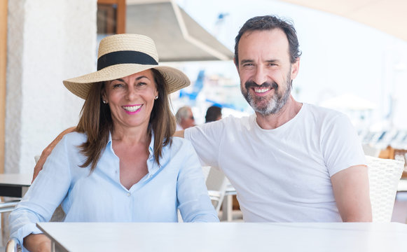 Middle age couple sitting at terrace with a happy face standing and smiling with a confident smile showing teeth