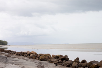 Sandy beach with wall rock duty low tide windy effect to fine sand reflect under sky at Trat Province of Thailand.