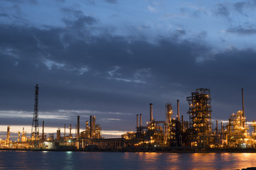 Petroleum refinery factory on water coast at dusk