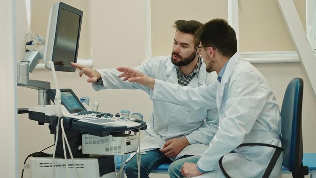 Two male doctors discussing ultrasound scanning research results