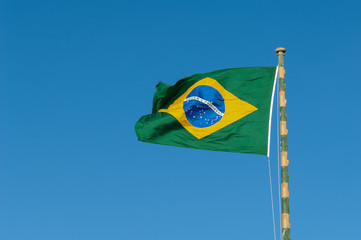 Brazil flag in the wind, contrasting with the blue sky, its colors means today: white is desire for peace, blue, sky and Brazilian rivers, yellow, the riches of the country, and green forests.